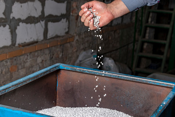 White granules of recycled plastic trash in the hand