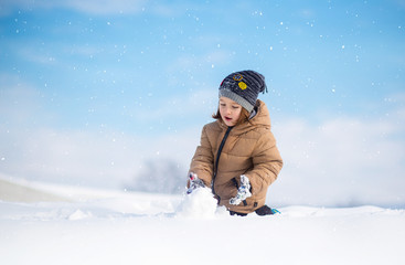 Fototapeta na wymiar Boy having fun, playing outside, surrounded with snow.