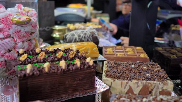 Grupo de tartas y turrones decorados y gente comprando