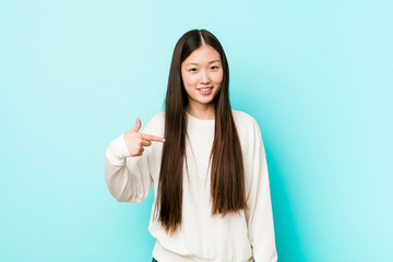 Young pretty chinese woman person pointing by hand to a shirt copy space, proud and confident