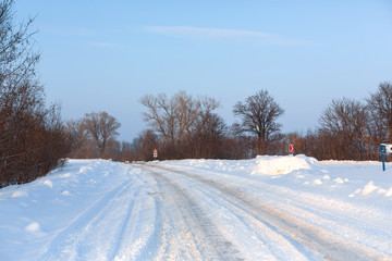 Obraz premium Winter poorly cleared road. Road in the countryside strewn with snow. Winter landscape with snowdrifts