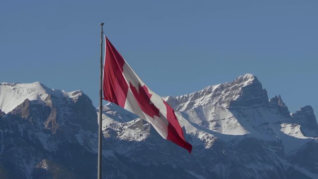 Canadian Flag Blowing in the Wind with Rocky Mountains in the Background, West Coast, Banff, Canmore, Alberta, Canada