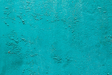 Grunge weathered cracked painted plastered wall closeup as turquoise background