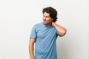 Obraz premium Young handsome man against a white background suffering neck pain due to sedentary lifestyle.