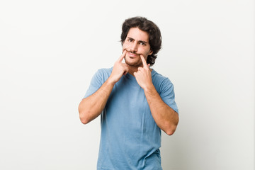 Young handsome man against a white background doubting between two options.