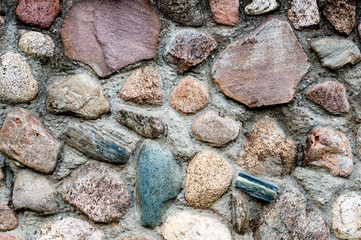 Background in the form of a fragment of a stone wall with textured stones from a colored rubble.