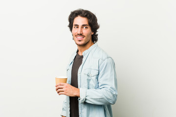 Young cool man drinking a coffee looks aside smiling, cheerful and pleasant.