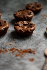 cocoa drink in blue mug with chocolate on dark textured background with chocolate muffins and vintage spoon and cocoa powder.