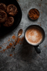 cocoa drink in blue mug with chocolate on dark textured background with chocolate muffins and vintage spoon and cocoa powder.