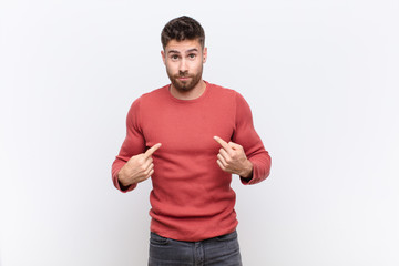 young handosme man pointing to self with a confused and quizzical look, shocked and surprised to be...