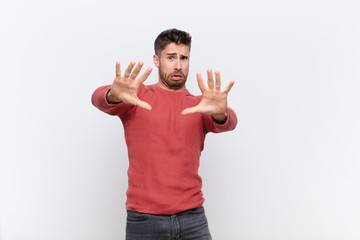 young handosme man feeling terrified, backing off and screaming in horror and panic, reacting to a...