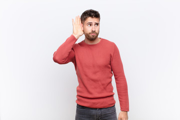 young handosme man looking serious and curious, listening, trying to hear a secret conversation or...