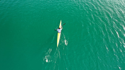 Obraz premium Aerial drone top down photo of fit women competing in sport canoe in tropical exotic lake with emerald waters