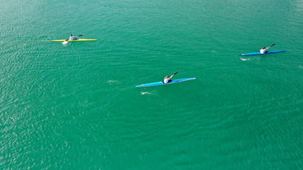 Aerial drone top down photo of fit women competing in sport canoe in tropical exotic lake with emerald waters