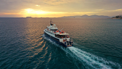 Aerial drone photo of yacht cruising leaving Marina Zeas at sunset with beautiful colours, Piraeus, Attica, Greece