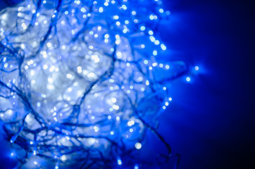 Abstract pattern of blue and white bokeh garland lights on a dark background