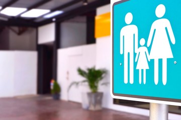 Focus at family restroom sign on metal pole with blurred background of outdoor bathroom in public...