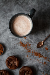 chocolate cocoa in blue mug on dark textured background with chocolate muffins and vintage spoon and cocoa powder.