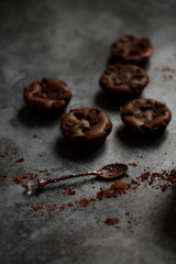 on a dark textured background with chocolate muffins and vintage spoon and cocoa powder.