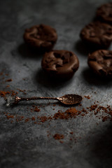 on a dark textured background with chocolate muffins and vintage spoon and cocoa powder.