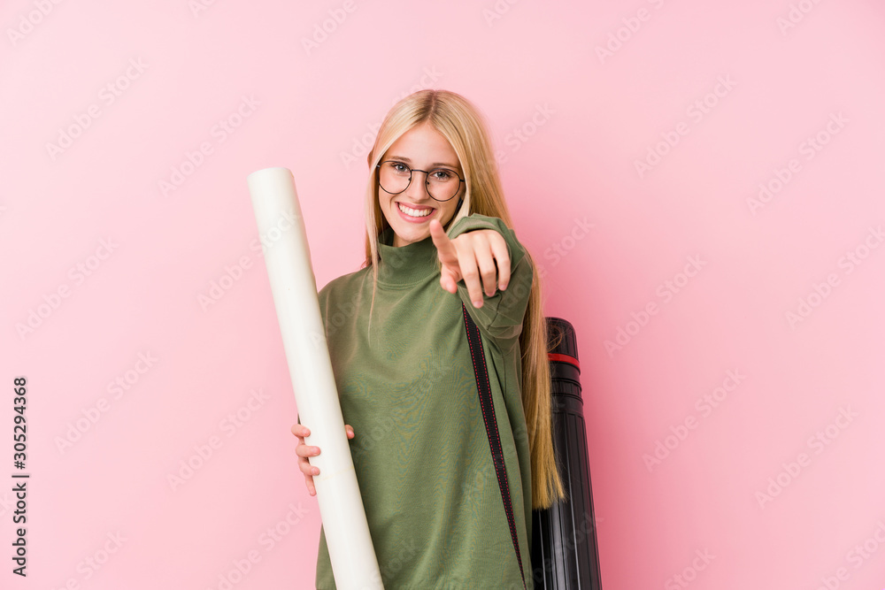 Wall mural Young blonde architecture student cheerful smiles pointing to front.