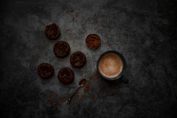 cocoa drink in blue mug with chocolate on dark textured background with chocolate muffins and vintage spoon and cocoa powder.