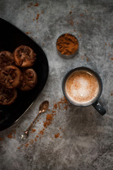 cocoa drink in blue mug with chocolate on dark textured background with chocolate muffins and vintage spoon and cocoa powder.