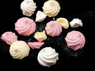 Color meringues on black background, close up