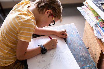 Portrait of cute boy with sketch pen and paper at desk in classroom. Russia, Krasnodar, May, 23,...
