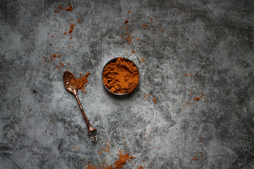 on a dark textured background vintage with a spoon and the cocoa powder.