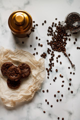on a light textured marble background, chocolate muffins on parchment paper with a vintage spoon and coffee beans top view.