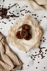 on a light textured marble background, chocolate muffins on parchment paper with a vintage spoon and coffee beans top view.