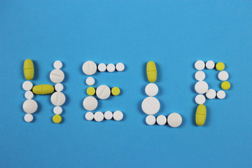 Word Help made by white and yellow pills on blue background