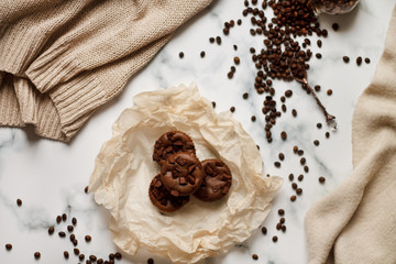 on a light textured marble background, chocolate muffins on parchment paper with a vintage spoon and coffee beans top view.