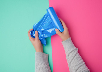 female hand unwinds a blue plastic bag for rubbish