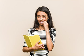Fototapeta premium Young asian woman student holding a book biting fingernails, nervous and very anxious.