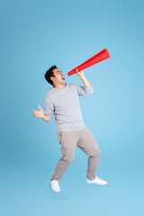 Asian man using red paper megaphone on blue background.
