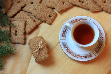 Gringerbread cookies and a cup of tea flat lay on a wooden surface.