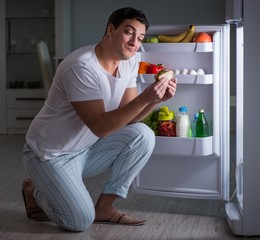 Man at the fridge eating at night