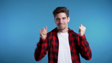 Yes winner gesture. Happy european man dancing. Handsome guy with stylish hairdo surprised to camera over blue background. 4k