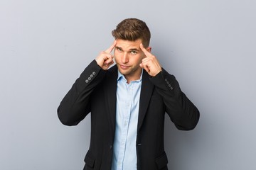 Young handsome caucasian man focused on a task, keeping forefingers pointing head.