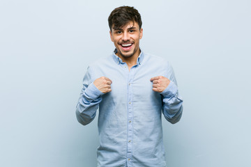 Young hispanic business man surprised pointing with finger, smiling broadly.