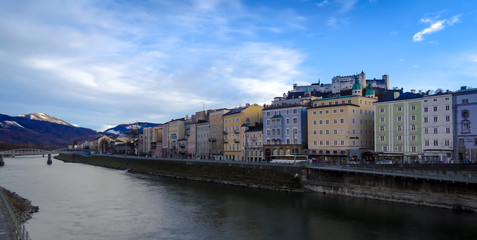 Fototapeta na wymiar Salzburg riverfront shops with river Salzach and castle Hohensalzburg in sunny daylight.