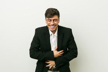 Young business hispanic man laughs happily and has fun keeping hands on stomach.