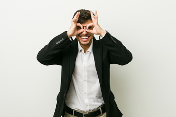 Young business hispanic man showing okay sign over eyes