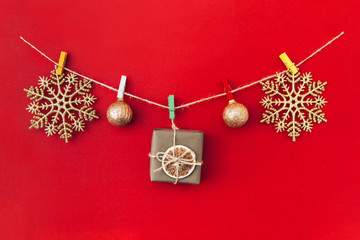 Christmas handmade garland made of golden snowflakes and other christmas decorations on red background.
