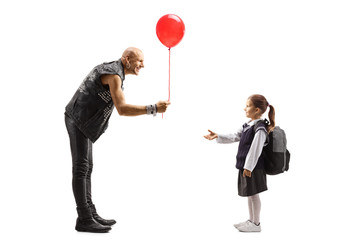 Obraz na płótnie Canvas Punker in leather clothes giving a red baloon to a schoolgirl
