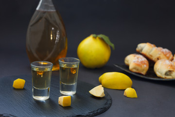 Quince brandy or quince vodka, hard liqueur, strong drink in a bottle and glasses on dark background. Serebian traditional dring, rakija or rakia.