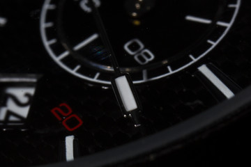 Macro detail of a man wristwatch, the dial is black with white and red details.