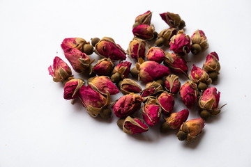 Dry tea rose buds on a white background in the shape of a heart
